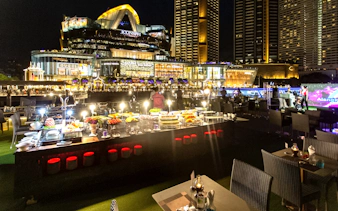 Dinner setup on Alangka Cruise with IconSiam in the background at night.
