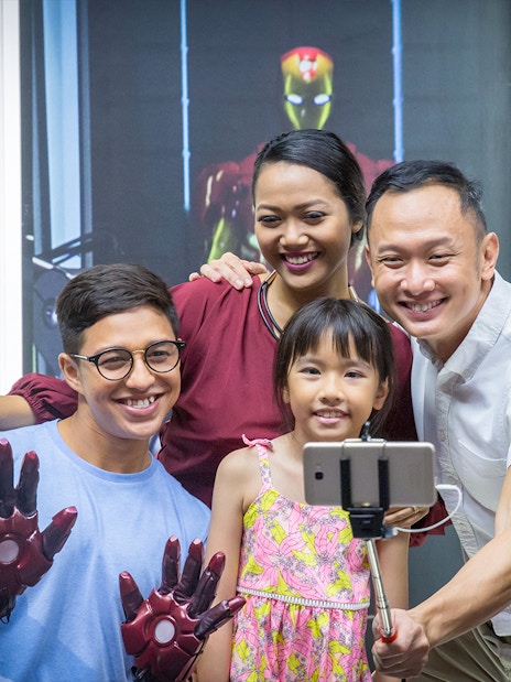 Family taking selfie with Iron Man figures at Madame Tussauds Singapore.
