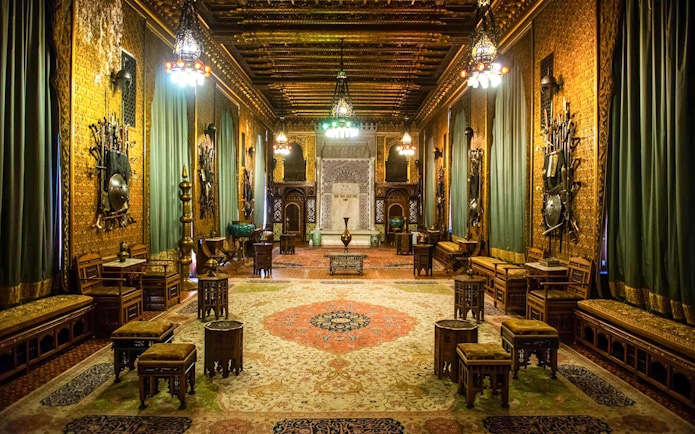 Ornate interior of Peleș Castle with intricate woodwork and decorative armor displays.