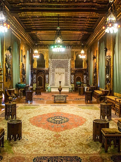 Ornate interior of Peleș Castle with intricate woodwork and decorative armor displays.