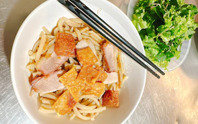 Vietnamese noodle dish with pork and crispy toppings, served with fresh greens in Da Nang.