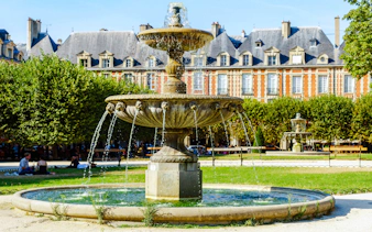 Fountain at Place des Vosges with historic buildings in Paris, France.