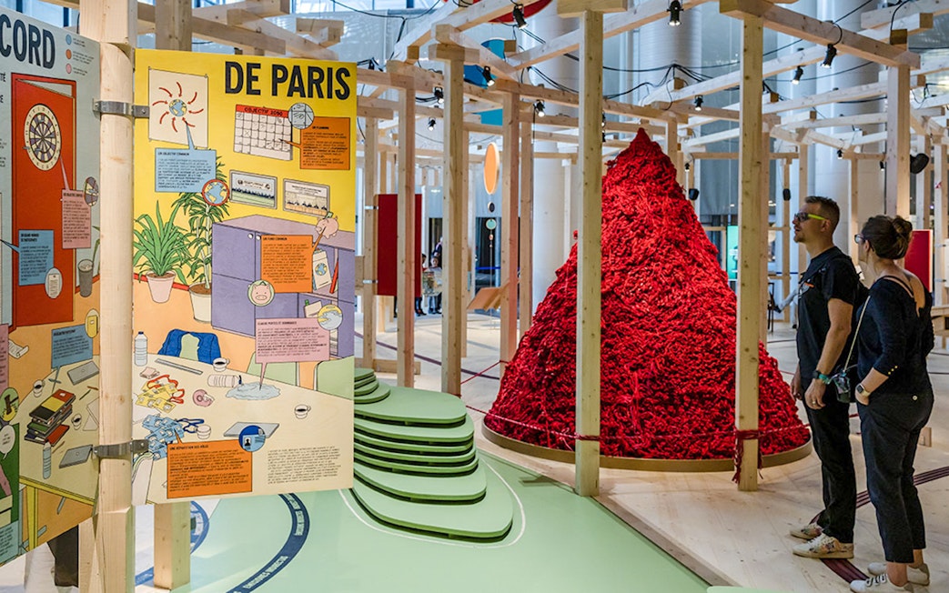 Exhibit at Paris museum with colorful educational panels and visitors observing a red art installation.