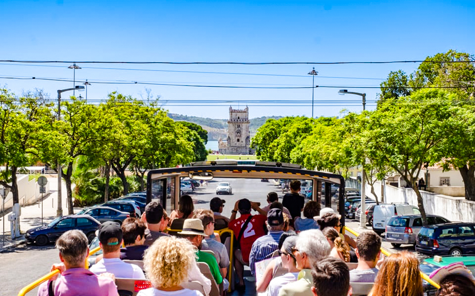 Tourists on Lisbon hop-on hop-off bus approaching Belém Tower.