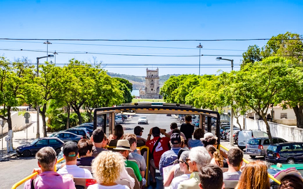 Tourists on Lisbon hop-on hop-off bus approaching Belém Tower.