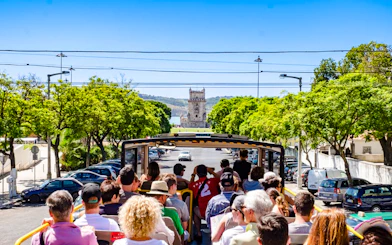 Tourists on Lisbon hop-on hop-off bus approaching Belém Tower.