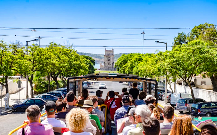 Tourists on Lisbon hop-on hop-off bus approaching Belém Tower.