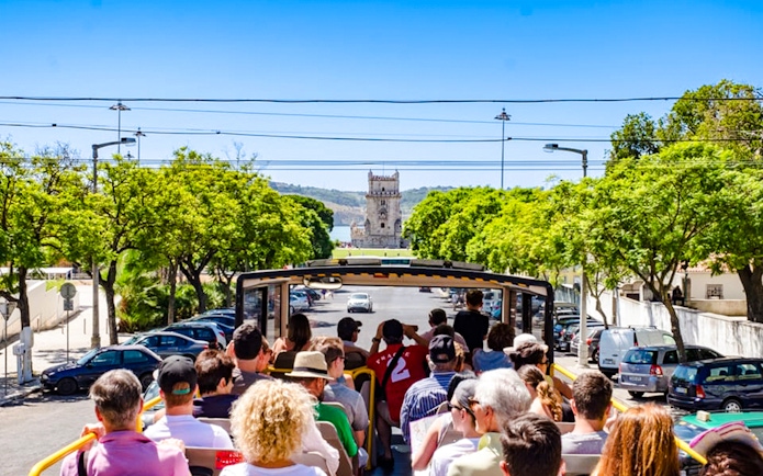Tourists on Lisbon hop-on hop-off bus approaching Belém Tower.