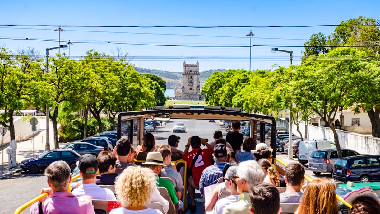 Tourists on Lisbon hop-on hop-off bus approaching Belém Tower.