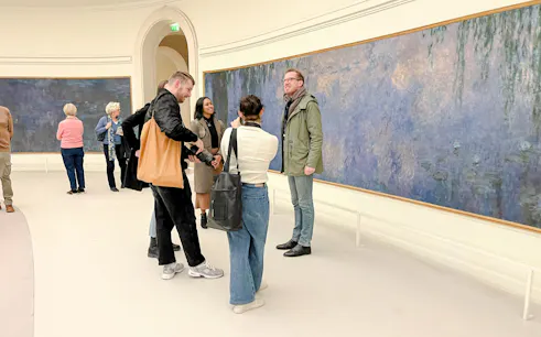 Visitors viewing Monet's Water Lilies at Orangerie Museum, Paris during guided tour.
