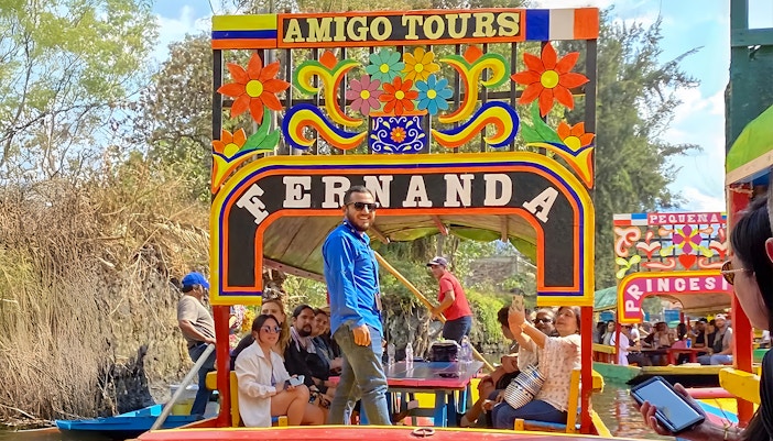 Trajinera boat with colorful decorations on Xochimilco canal, Mexico City, featuring lively party atmosphere.