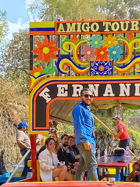 Trajinera boat with tourists on Xochimilco canal, Mexico City.