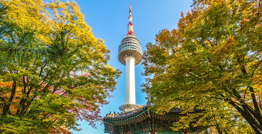 Namsan Seoul Tower above autumn trees and Korean pavilion.