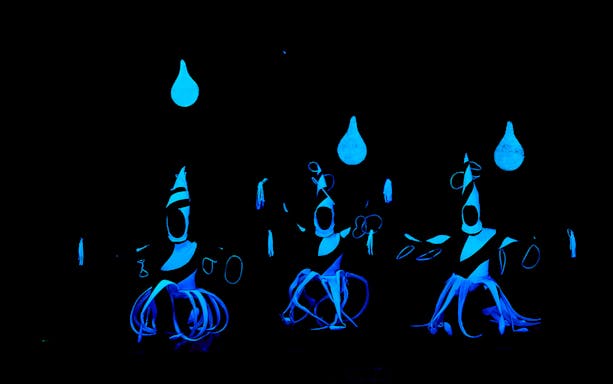 Black light theater performers in glowing costumes at WOW Show, Prague.