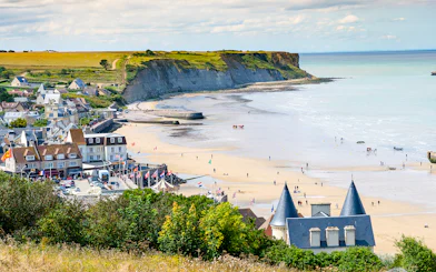 Arromanches Les Bains beach with cliffs and village in Normandy, France.
