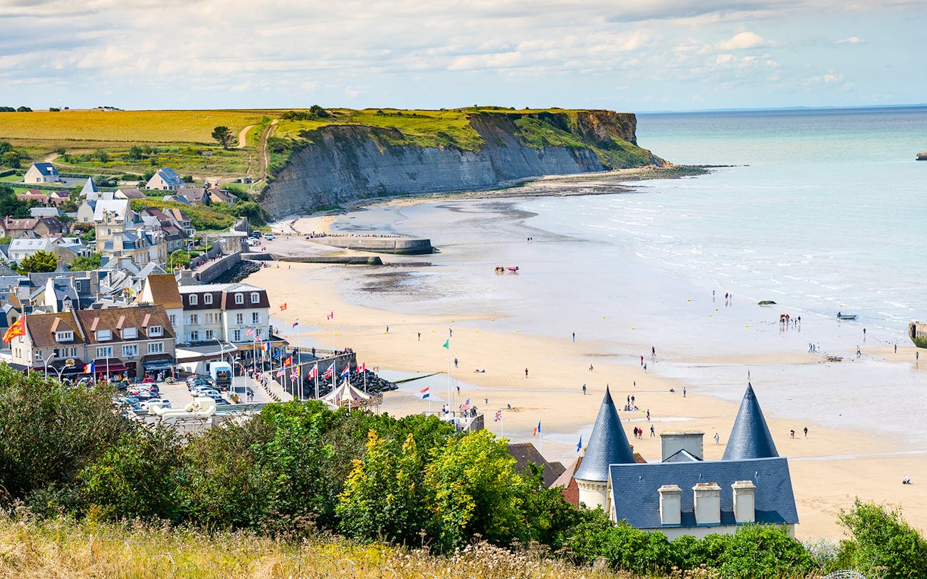 Arromanches Les Bains beach with cliffs and village in Normandy, France.