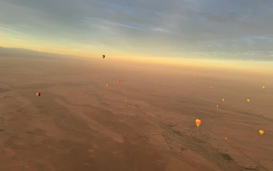 Hot air balloons floating over Marrakech desert at sunrise.