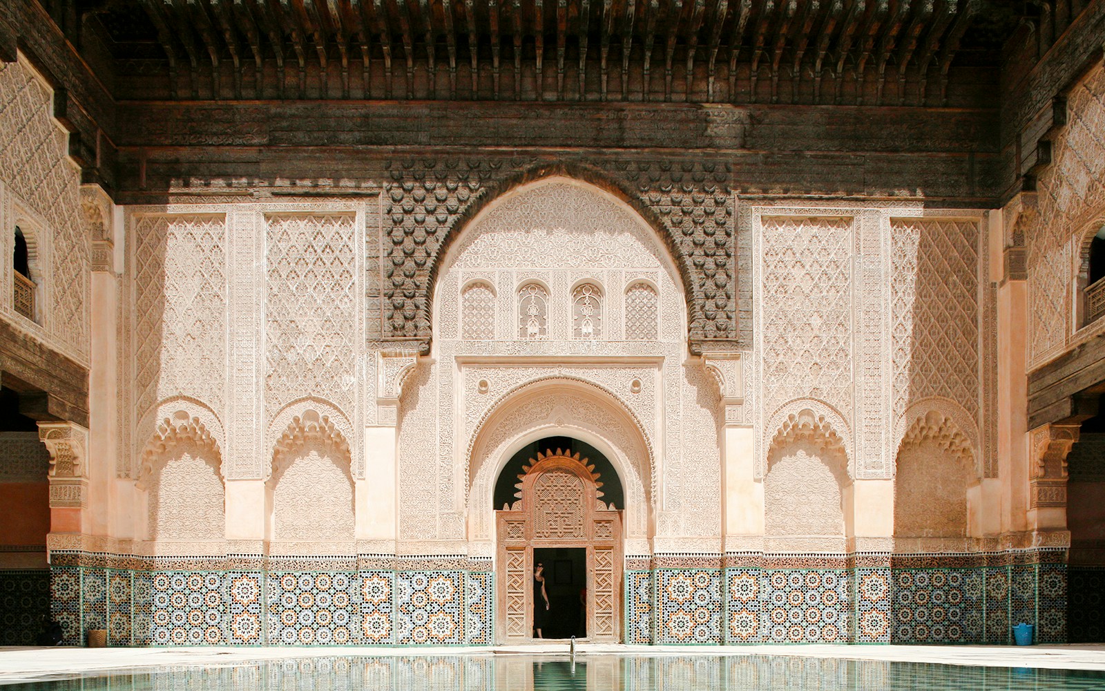 Ben Youssef Madrasa courtyard with intricate tilework and carved archways in Marrakesh, Morocco.