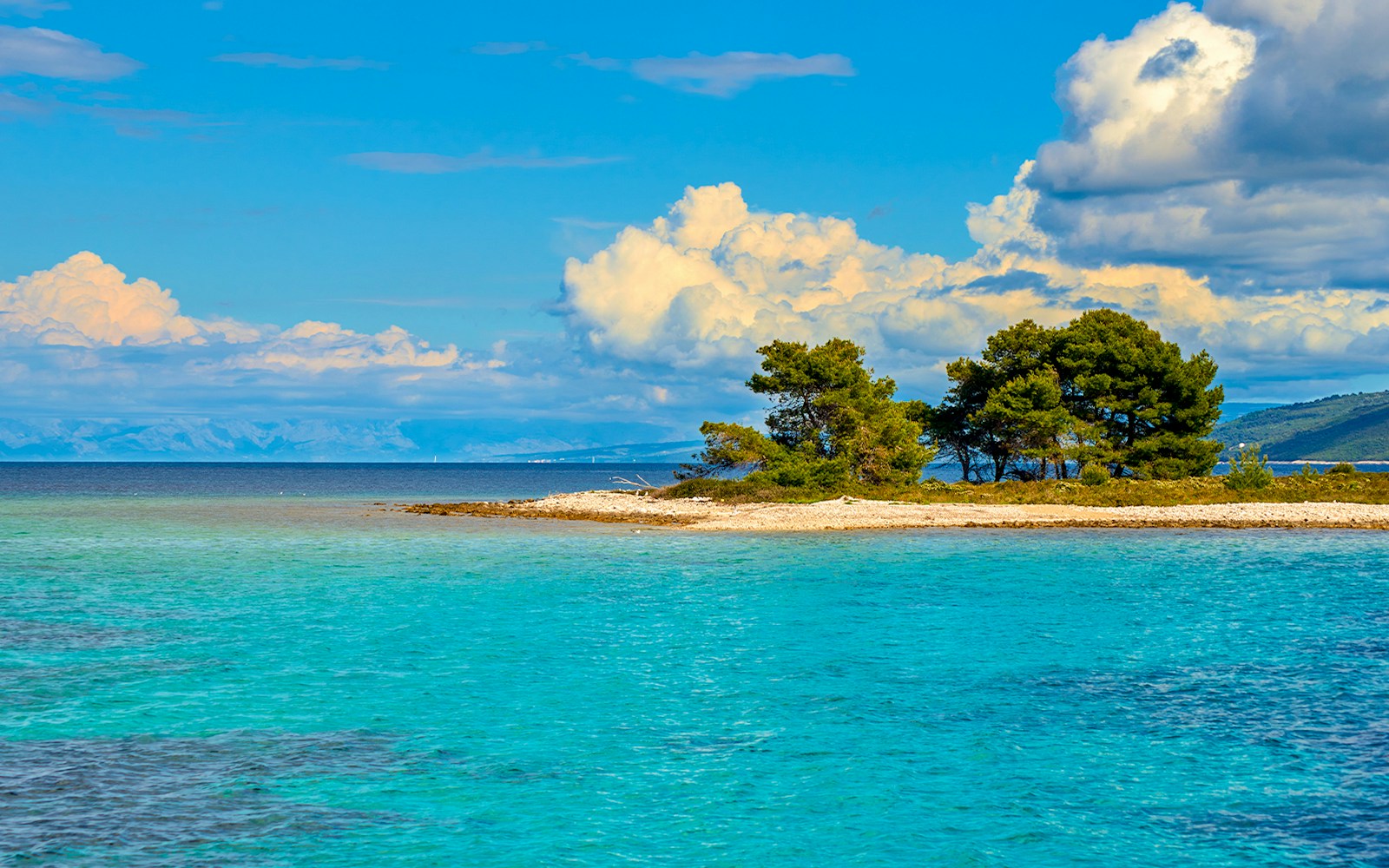 Blue lagoon with clouds and small island in Otok Krknjas Veli, Mediterranean Sea, Croatia.