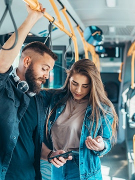Passengers looking at a phone on a city bus.