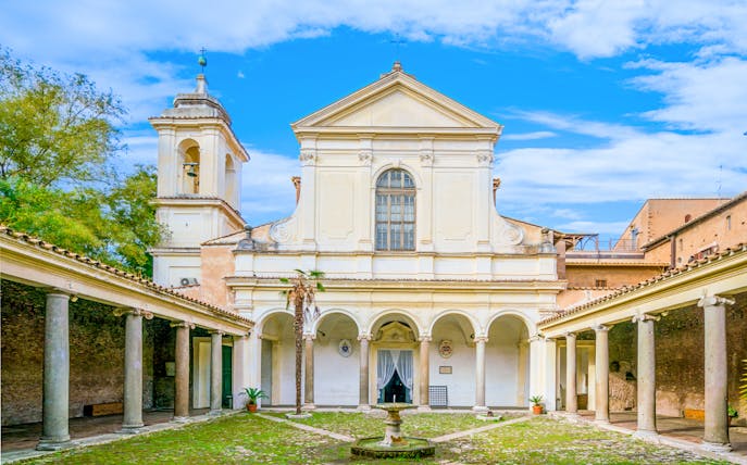 Courtyard of Basilica of San Clemente, Rome, with arches and bell tower.