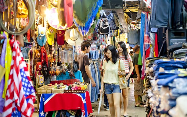 Shoppers exploring a vibrant market in Kuala Lumpur with colorful stalls and local goods.