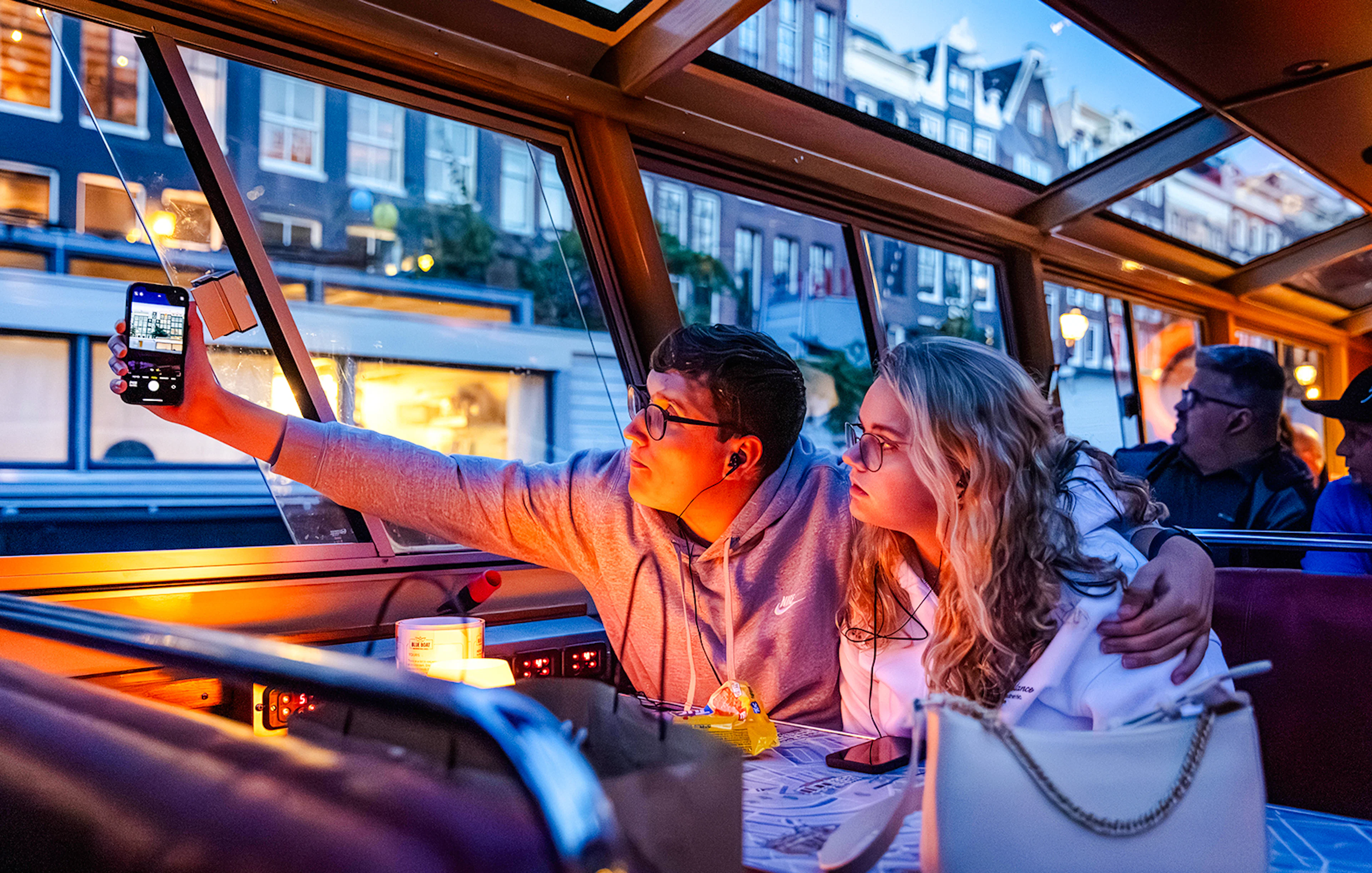 Guests enjoying a winter evening cruise in Amsterdam, taking photos through the boat window.