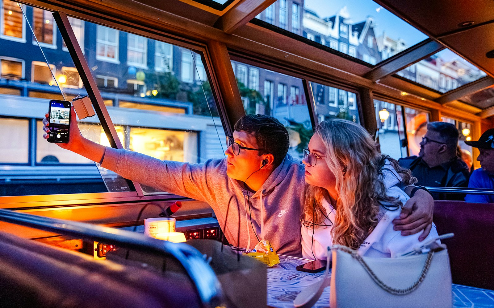 Guests enjoying a winter evening cruise in Amsterdam, taking photos through the boat window.