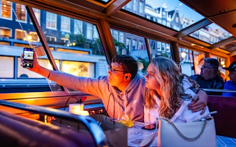 Guests enjoying a winter evening cruise in Amsterdam, taking photos through the boat window.