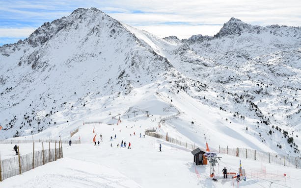 Skiers on snowy slopes in Andorra with mountain backdrop during a tour from Barcelona.