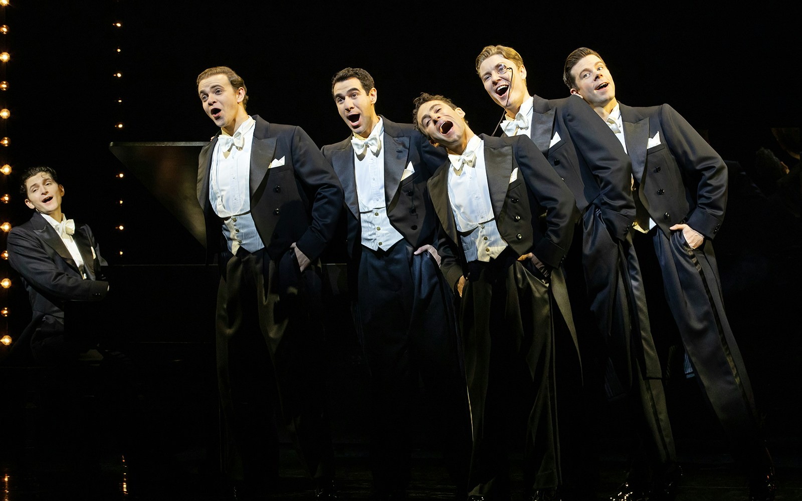 Performers in tuxedos singing on stage in "Harmony: A New Musical.