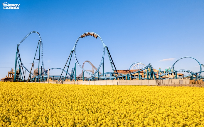 Rollercoaster at Energylandia Theme Park, Zator, Poland, with yellow flowers in foreground.