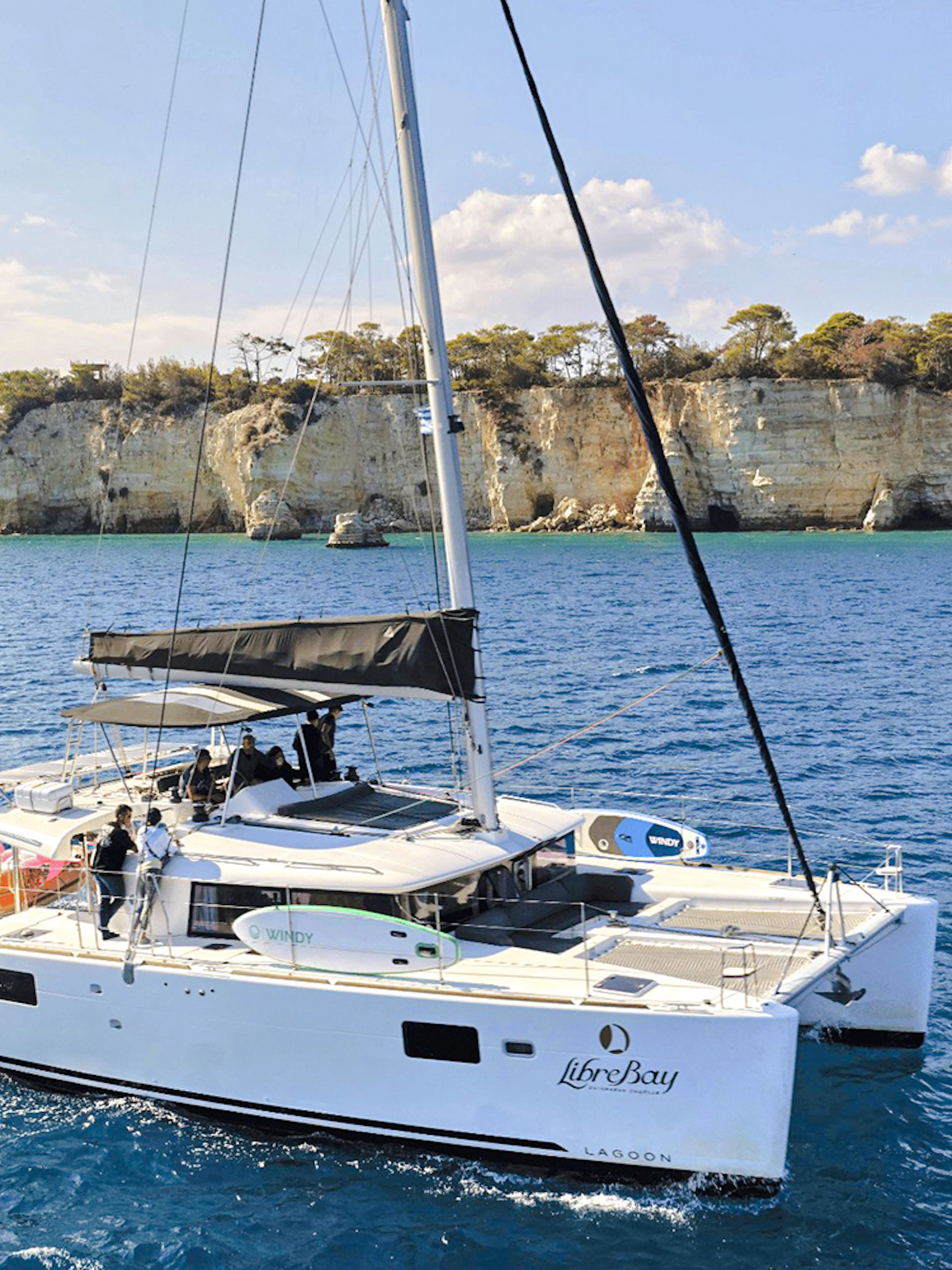 Catamaran sailing near rocky cliffs during Souda to Marathi Bay cruise.