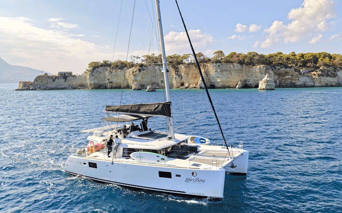 Catamaran sailing near rocky cliffs during Souda to Marathi Bay cruise.