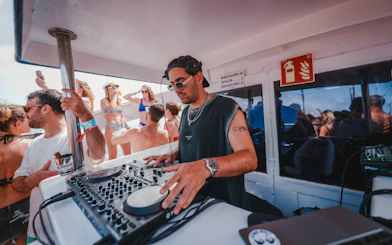 DJ performing on Cruise Crush Boat Party with guests dancing in the background.