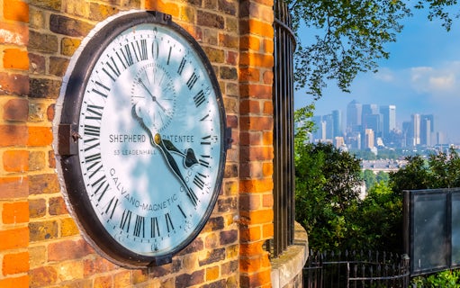 Shepherd Gate Clock at Royal Observatory Greenwich with London skyline in background.