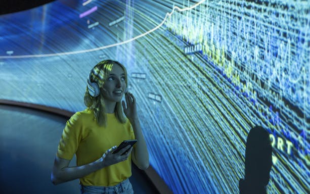 Visitor using audio guide inside Glories Skyline Tower exhibition.