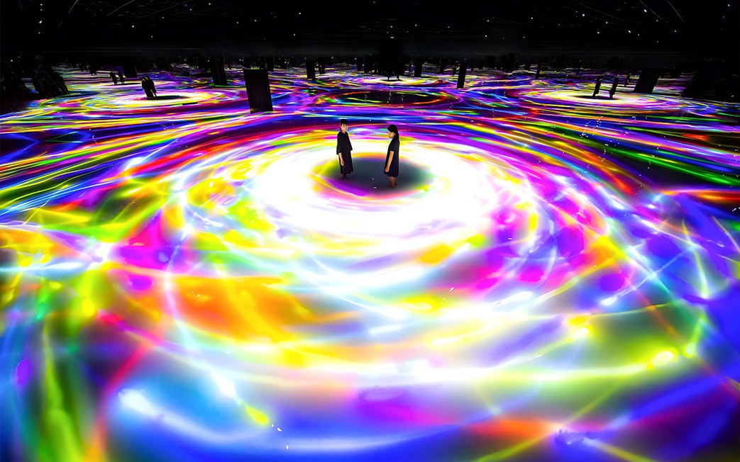 Visitors standing in colorful digital art installation at TeamLab Planets, Tokyo.