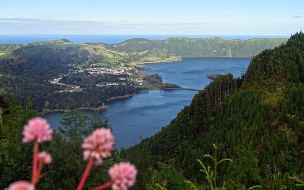 Sete Cidades crater lake view with lush green hills and distant village.