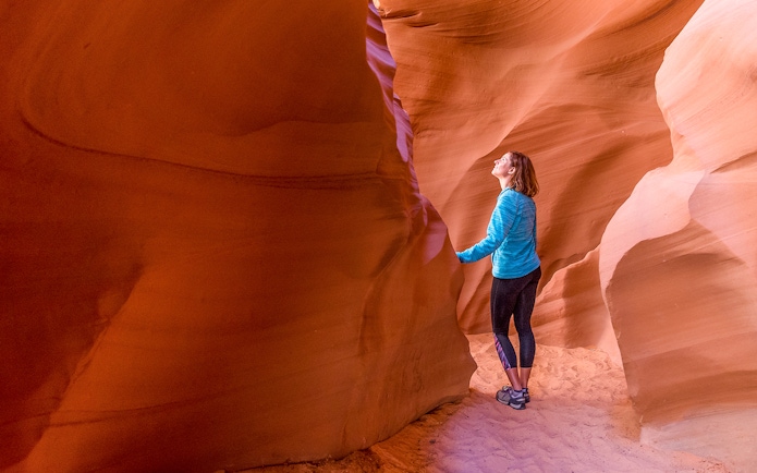 Young woman exploring the sandstone formations of Antelope Canyon, Arizona.