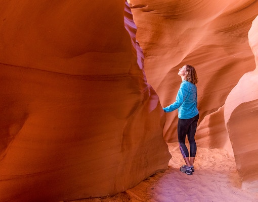 Young woman exploring the sandstone formations of Antelope Canyon, Arizona.