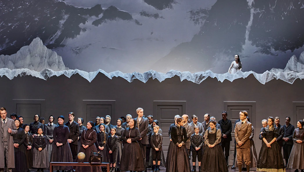 Opera performance of La Sonnambula with cast on stage and mountain backdrop.