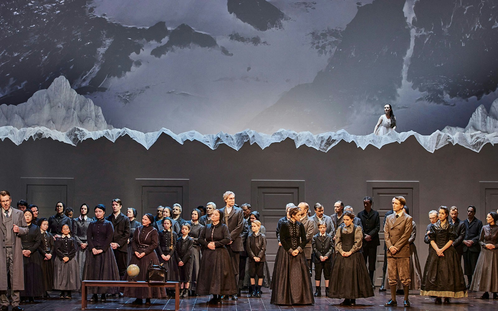 Opera performance of La Sonnambula with cast on stage and mountain backdrop.