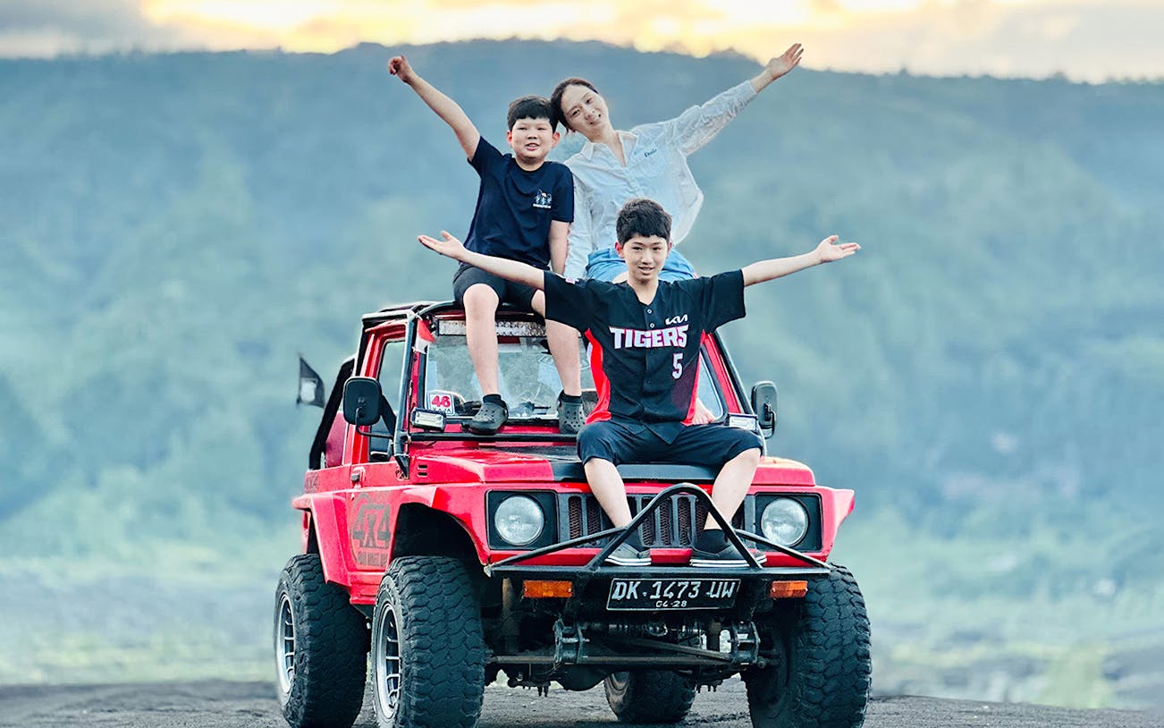 Family enjoying Kintamani sunset on a red 4WD jeep tour.