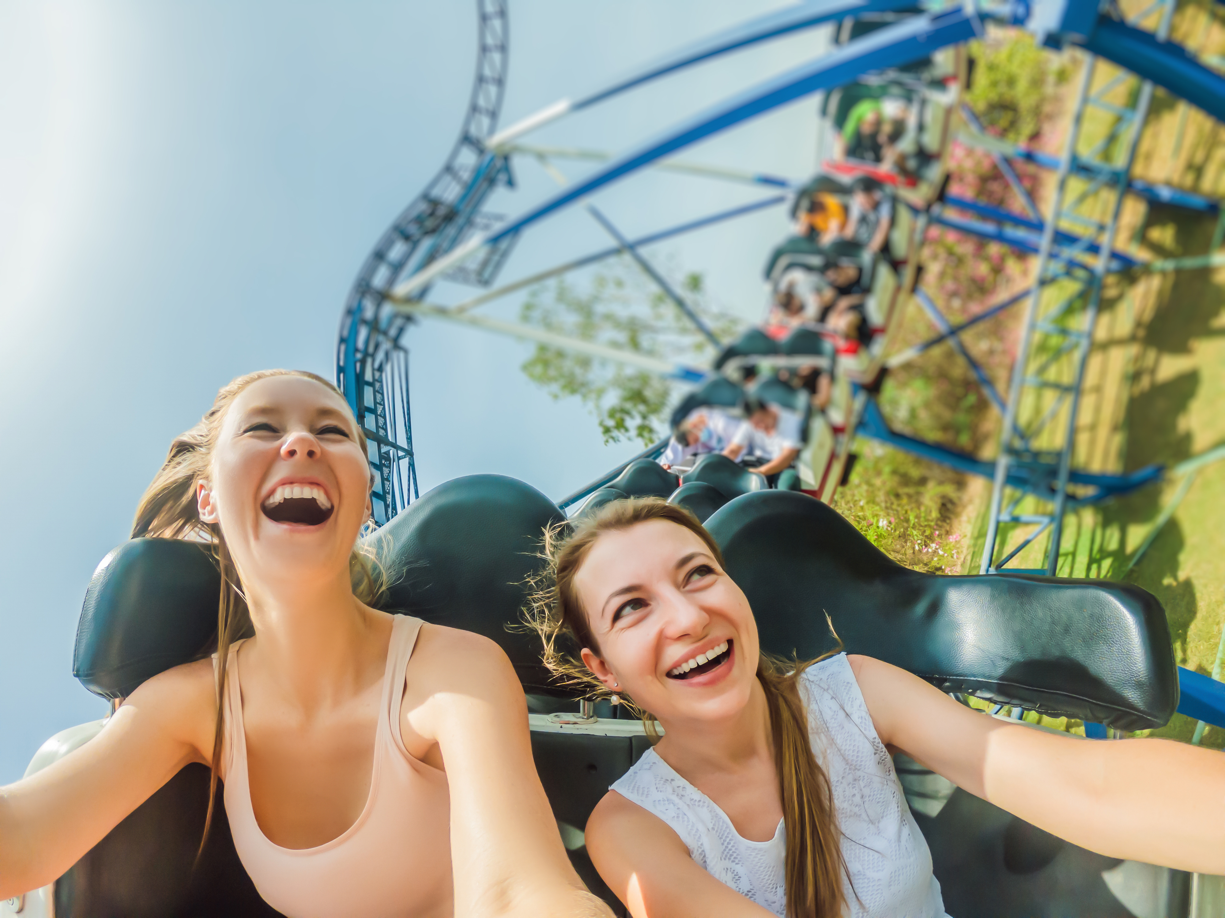 Two girls enjoying a rollercoaster ride, smiling with excitement.