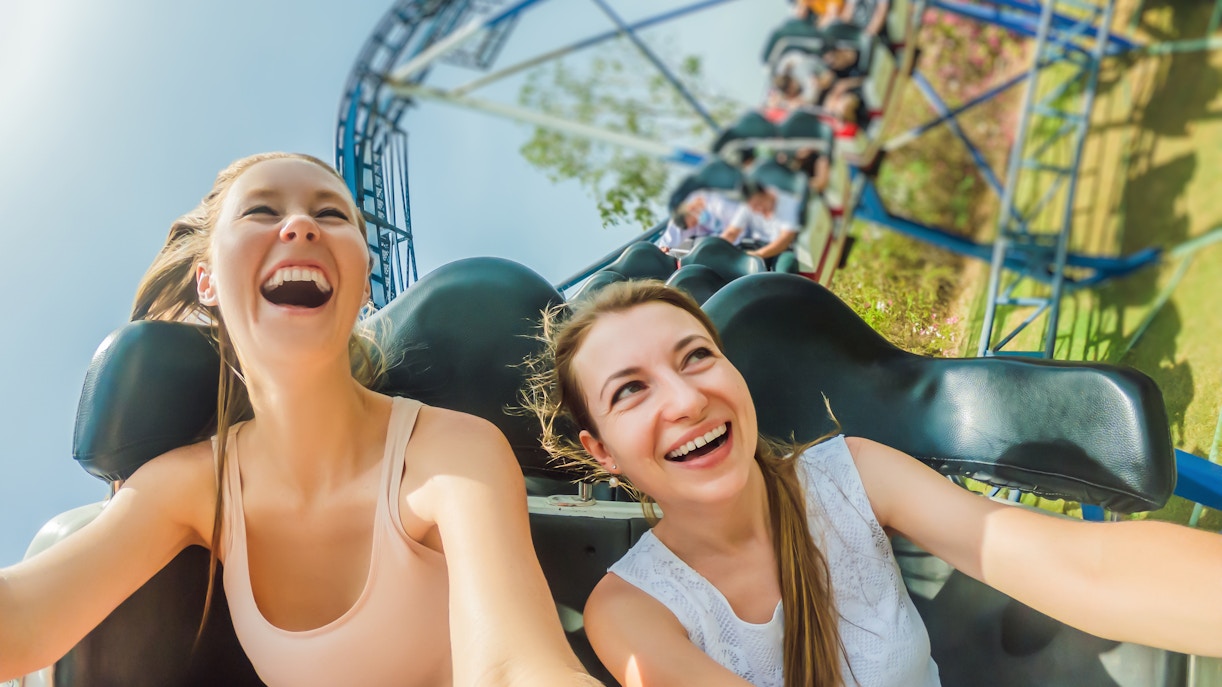 Two girls enjoying a rollercoaster ride, smiling with excitement.