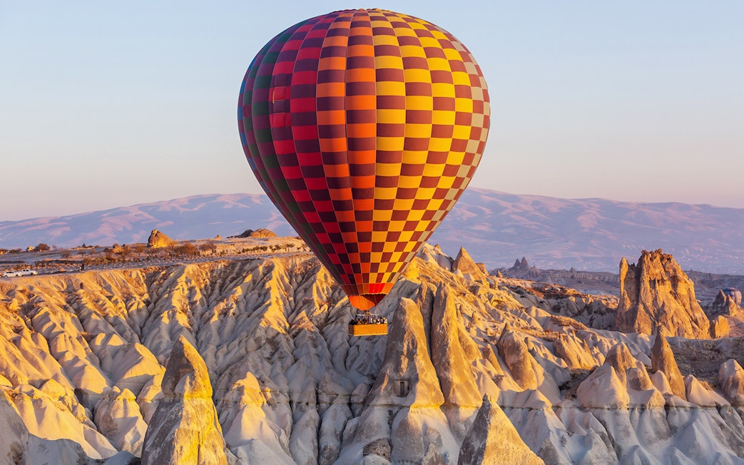 Hot air balloon over Cappadocia's unique rock formations at sunrise.