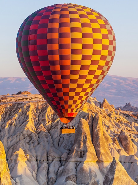 Hot air balloon over Cappadocia's unique rock formations at sunrise.