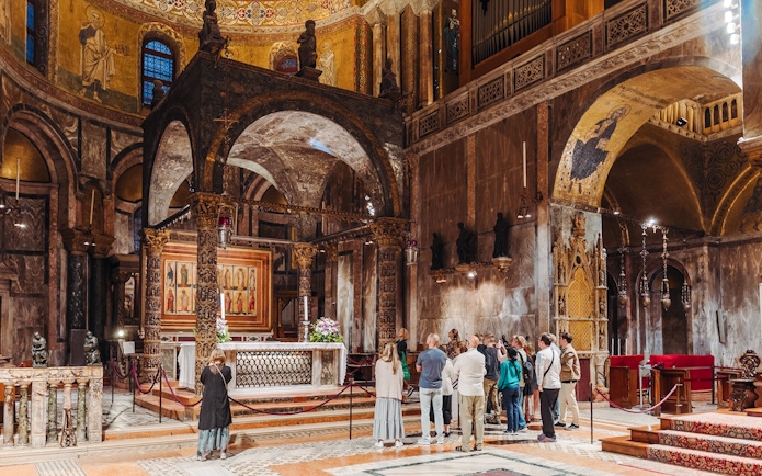 Visitors on an exclusive tour inside St. Mark's Basilica, Venice, admiring the ornate interior.