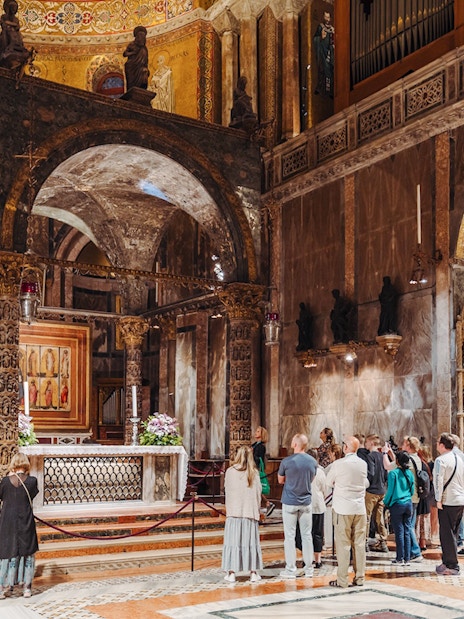 Visitors on an exclusive tour inside St. Mark's Basilica, Venice, admiring the ornate interior.